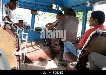 Un chauffeur lutte avec le levier sur ce très vieux bus. Le véhicule est plein de passagers payants mais est en très mauvais état. Le bus est un des nombreux autobus anciens encore en usage sur l'île de Fidji en 2018. La population locale dans la ville de Nadi ne se plaignent pas que le mode de vie est très décontracté et les tarifs sont bon marché. Banque D'Images