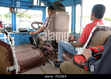 Un chauffeur lutte avec le levier sur ce très vieux bus. Le véhicule est plein de passagers payants mais est en très mauvais état. Le bus est un des nombreux autobus anciens encore en usage sur l'île de Fidji en 2018. La population locale dans la ville de Nadi ne se plaignent pas que le mode de vie est très décontracté et les tarifs sont bon marché. Banque D'Images