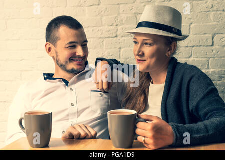 La fille et le gars dans un café, à une table, de parler. Le couple d'amoureux s'assoit dans un café, pourparlers, dispose d'un plateau. La jeune fille et l'homme s'asseoir dans un café et communiquer. Banque D'Images