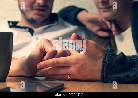 L'homme la main caresse une femme de main. Dans le contexte de l'homme heureux et la jeune fille sont visibles. Devant eux sur une table se trouve le téléphone. La phot Banque D'Images