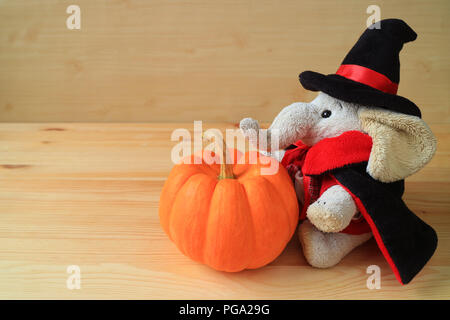 Doudou éléphant mignon en costume de l'assistant avec un brillant couleur orange citrouille mûre isolé sur la table en bois Banque D'Images