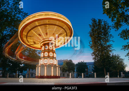 Éclairées Carrousel rotatif à grande vitesse Merry-Go-Round. Soirée d'été dans le parc d'attractions de la ville. Banque D'Images