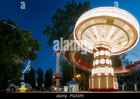 Éclairées Carrousel rotatif à grande vitesse Merry-Go-Round. Soirée d'été dans le parc d'attractions de la ville. Banque D'Images