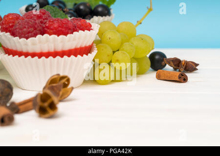Fruits tropicaux frais et épices still life with raspberries in cup cake porteurs, les raisins, les bleuets, la cannelle et la badiane, avant-plan copy space Banque D'Images