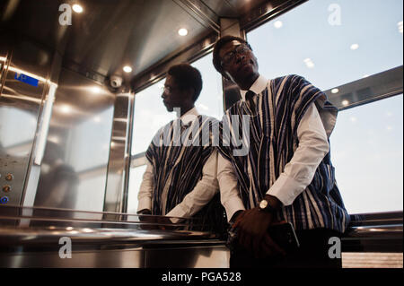 Homme africain en vêtements traditionnels et lunettes à ascenseur ou d'un ascenseur moderne. Banque D'Images