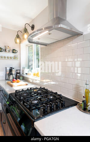 Une cuisinière à gaz dans une maison moderne équipée avec une hotte électrique avec un dosseret de carreaux blancs Banque D'Images