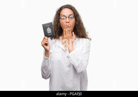 Young hispanic woman holding Passport Canada de couvrir la bouche à part choqué avec honte pour erreur, expression de la peur, peur en silence, secret co Banque D'Images