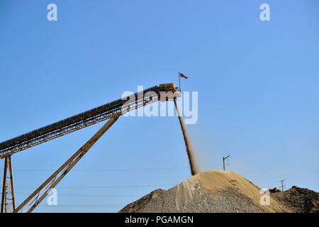 L'Elgin, Illinois, USA. Un tapis roulant fournit la pierre et le gravier pour former un gros tas de matériau à un béton prêt à l'usine. Banque D'Images