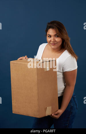 Jeune fille avec un carton grand fort isolé sur fond bleu Banque D'Images