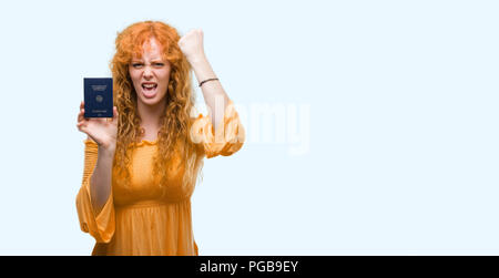 Jeune femme rousse holding passport de l'Allemagne contrarié et frustré de crier avec colère, fou et hurlant de main levée, la colère concept Banque D'Images
