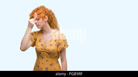 Jeune femme rousse fatigué se frottant le nez et les yeux sentant la fatigue et les céphalées. Le stress et la frustration concept. Banque D'Images