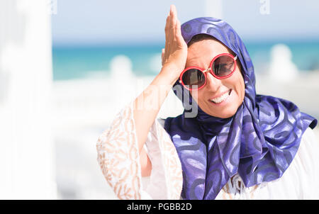 L'âge moyen de la femme arabe brune portant des lunettes de piscine a souligné avec la main sur la tête, choqué de honte et de surprise, de colère et de frustration face Banque D'Images