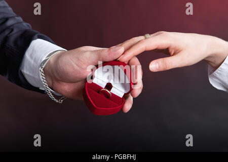 L'homme donne une bague de fiançailles en or pour femme en rouge Banque D'Images