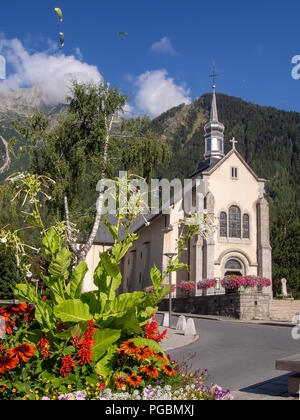 Chamonix Mont Blanc, Haute Savoie, France. Vue sur la place avec l'église catholique de St Michel en été avec des fleurs et de parapente. La ville est une destination touristique populaire toute l'année. Banque D'Images