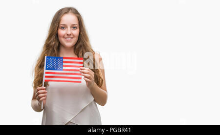 Jeune blond woman holding pavillon de l'USA avec un visage heureux et souriant debout avec un sourire confiant montrant les dents Banque D'Images