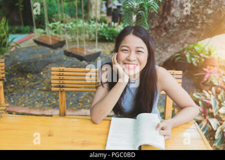 Asian girl teen sourire lecture réserve en maison de vacances Banque D'Images