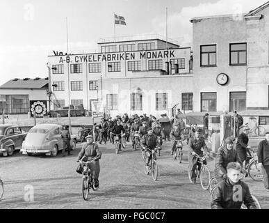 Factory dans les années 1950. Le travail est terminé pour la journée à la location et de l'entreprise moto Monark en Suède. Les travailleurs quittent l'usine s'appuyant sur leurs vélos et cyclomoteurs. Suède 1958 Banque D'Images