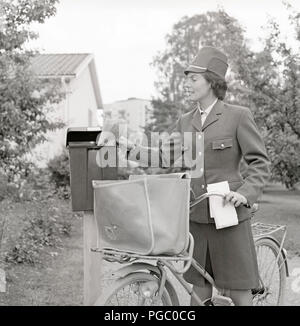 1960 Facteur. Une femme dans le service postal suédois offre uniforme mail et mettre les lettres dans une boîte aux lettres. La Suède des années 1960. Kristoffersson Photo DG114-7 Banque D'Images