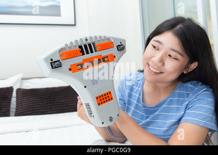 Profitez de fille à l'aide d'aspirateur d'acariens à l'aide d'un matelas lit avec lampe UV de l'éliminateur de poussière Banque D'Images