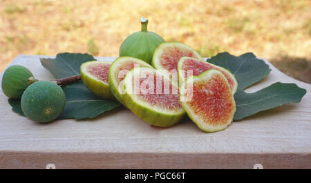 Les tranches de figues fraîches et entières avec des feuilles sur une planche en bois avec de l'espace libre pour le texte Banque D'Images