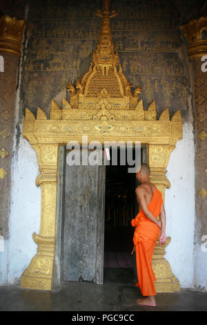 Le moine bouddhiste en face d'une porte à Vat Xieng Thong de Luang Prabang , Laos Banque D'Images