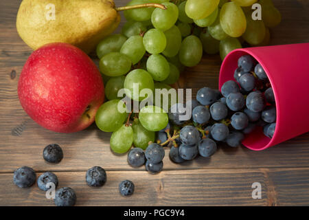 Mélange de fruits juteux et de baies. Poire, pomme, raisin vert et bleu, les bleuets sur fond de bois rustique gris pour le texte de l'espace Banque D'Images