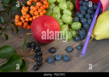 Mélange de fruits juteux et de baies. Poire, pomme, raisin vert et bleu, bleuets, Rowan et aronia gris sur fond de bois rustique de l'espace pour tex Banque D'Images