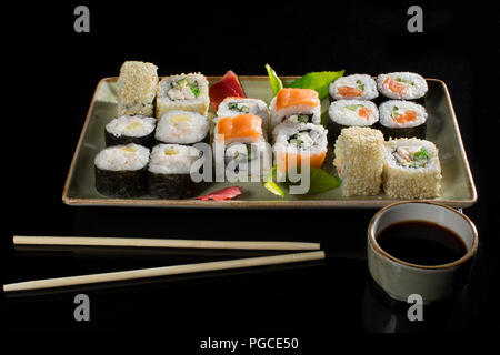 Menu du restaurant japonais. Plusieurs sushi bordée sur une plaque avec des bâtons de bambou et de la sauce soja.Vue sur les rouleaux d'en haut Banque D'Images