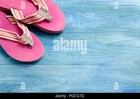 Chaussons rose sur un fond de bois bleu, été Contexte et concept de vacances Banque D'Images
