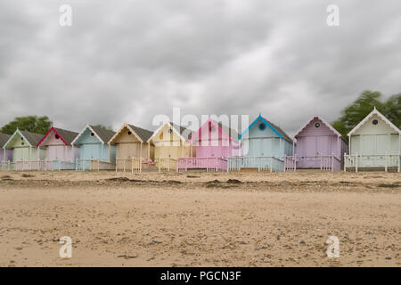 Cabines colorées sur la plage sur l'île de Mersea, Essex. Banque D'Images