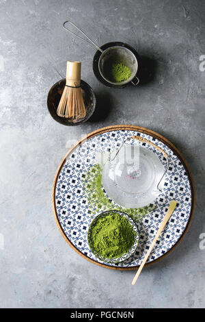 Ingrédients pour faire boire le matcha. Le thé vert matcha en poudre dans un bol en céramique, traditionnel bambou cuillère et fouetter sur plaque décorative, théière en verre ove Banque D'Images