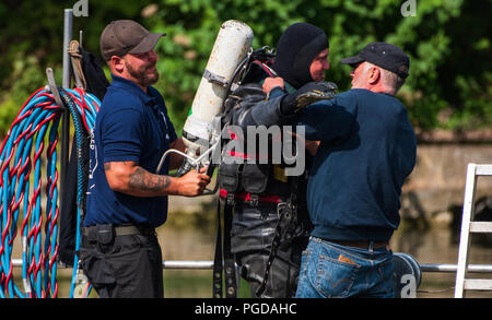 Sennfeld, Allemagne. Août 24, 2018. Deux racleurs des explosifs et munitions préparer une combinaison de plongée du collègue pour une plongée dans le lac de baignade Sennfeld. Le faible niveau de l'eau causée par la chaleur de révéler les sites contaminés explosive sous la forme d'armes à sous-munitions, les bombes et les armes trouvées dans les eaux de la Bavière. Crédit : Nicolas Armer/dpa/Alamy Live News Banque D'Images