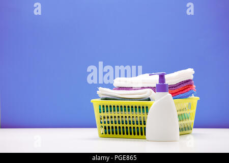 Photo d'une bouteille de savon liquide et de serviettes colorées dans panier isolé sur fond bleu Banque D'Images