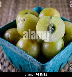 L'amla (groseille indienne aka, Phyllanthus emblica) dans un panier bleu produire. Un fruit est afficher en coupe. Banque D'Images