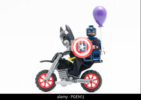 Batman avec Captain America holding balloon équitation moto. Figurines Lego sont fabriqués par le groupe Lego. Banque D'Images