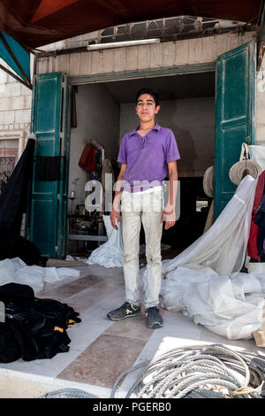 Hébron, en Palestine, le 3 août 2014 : jeunes adultes palestiniens se tenir dans une porte d'un atelier de sciage. Banque D'Images