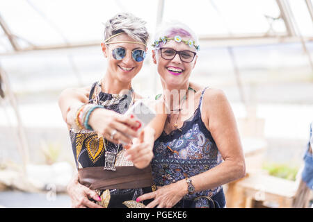 Couple hippie de blancs belle les femelles utilisent un téléphone intelligent. Différents âges attrayant nice les gens à rester ensemble en toute sécurité avec une assurance activité de loisirs avec fri Banque D'Images