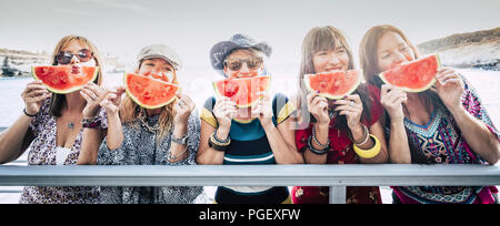 Groupe de nice cute cheerful young women friends rester ensemble s'amuser et profiter de l'amitié prendre une pastèque rouge près de l'expression de visage. Banque D'Images