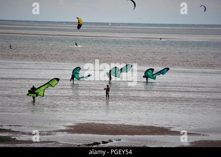 Groupe de surfeurs , para planeurs, marchant sur la plage de Hunstanton en pleine tempête Banque D'Images