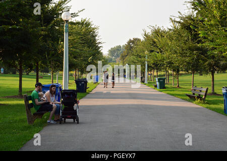 Les résidents de la ville se détendre le long d'un chemin bordé d'arbres à Chiago de Lincoln Park. Banque D'Images