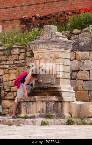 Femme utilisant une fontaine d'eau dans le village espagnol de Castrojeriz tout en valant le Camino de Santiago le chemin de Saint-Jacques route de pèlerinage Espagne Banque D'Images