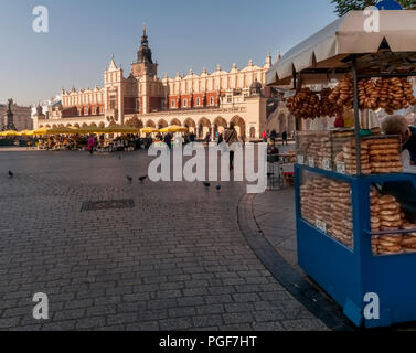 Krakowski Obwarzanek vendeur de rue à la place du marché et Halle aux draps dans l'arrière-plan, Cracovie, Pologne Banque D'Images