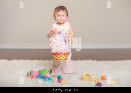 Cute adorable Caucasian baby girl in pink shirt et pantalon célébrer Pâques fête chrétienne traditionnelle. Kid enfant holding basket et jouer avec Banque D'Images