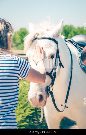 Jeune femme caressant beaux cheval blanc. L'amitié, de partenariat et de confiance. Banque D'Images