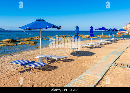 Passerelle en bois et de chaises longues avec parasols sur la magnifique plage de Kolymbia. L'île de Rhodes, Grèce Banque D'Images