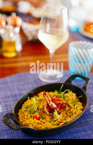 Risotto aux fruits de mer délicieux servi avec du vin blanc pour le déjeuner ou le dîner Banque D'Images