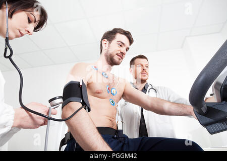 Médecin et l'infirmier aider le patient pendant l'examen médical de test de stress cardiaque Banque D'Images