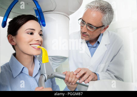 Young woman portrait ayant une vue panoramique sur la radiographie numérique de ses dents avec un médecin d'âge moyen dans le cabinet dentaire. Banque D'Images