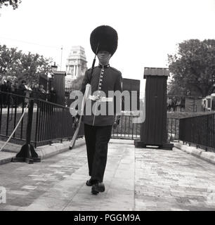 Années 1960, historiques, une reine ou garde royale sur l'exécution de son bearskin, avec carabine, Tour de Londres, Londres, Angleterre, Royaume-Uni. Banque D'Images