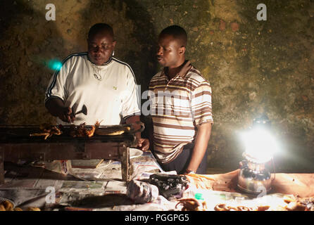 STONE TOWN, ZANZIBAR, TANZANIE - JUILLET 05 2008 : deux hommes grillent des fruits de mer. Scène à un marché de nuit à Stone Town, Zanzibar. Banque D'Images